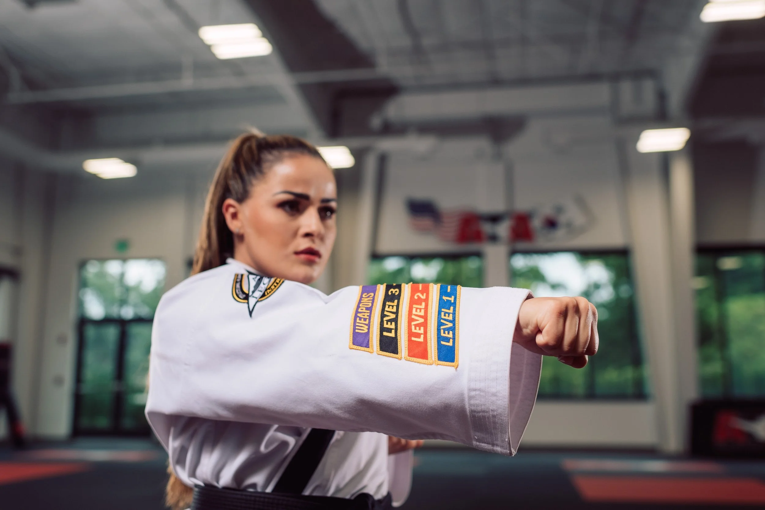 Teens and Adults student in a black belt uniform practicing a punching technique during class